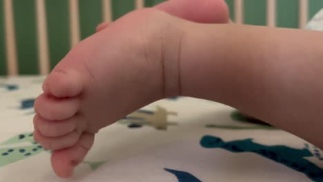 happy 2 month old newborn baby kicking his legs and feet on his crib