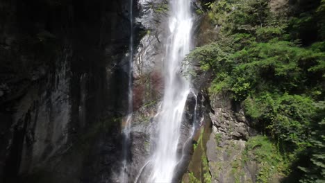 Aerial-view-of-waterfall-surrounded-by-green-planets-and-stones