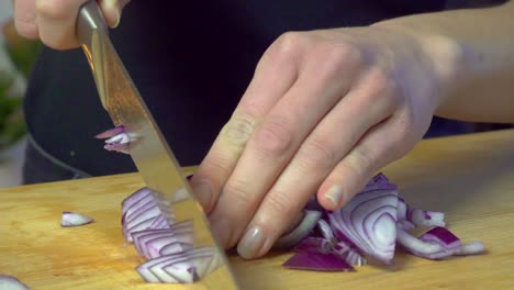 female hands chopping red onions on cutting board