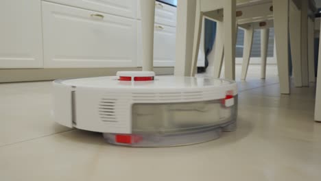 white robot vacuum cleaner performs automatic cleaning of the apartment, modern technology of smart cleaning.
