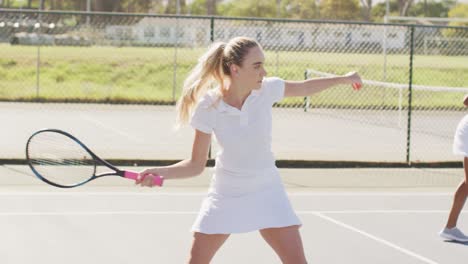 Video-of-caucasian-female-tennis-player-holding-racket-and-training-with-friend