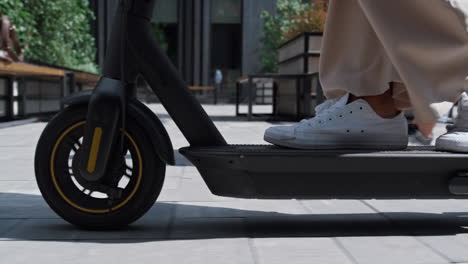 closeup female legs riding kickscooter in white sneakers. urban traveler concept