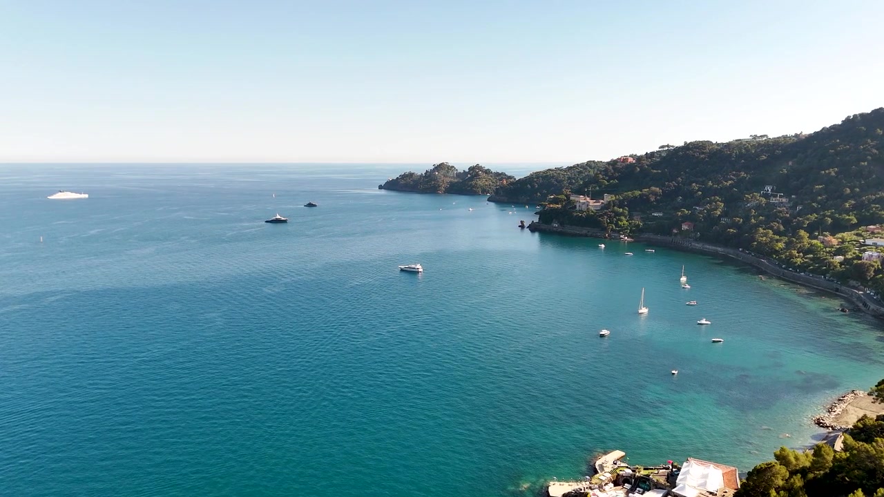 Ripresa aerea dall'alto di una baia panoramica con acqua turchese e colline verdi e lussureggianti.
