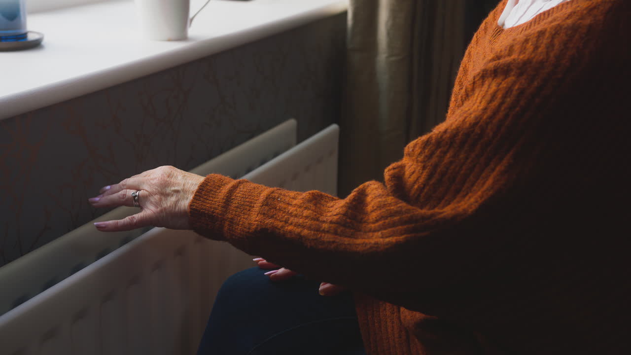 생활 비용 에너지 위기에서 라디에이터에 의해 에너지 청구서와  ⁇ 체어를 타고 있는 노인 여성