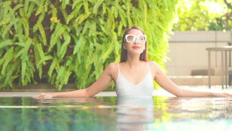 elegante mujer asiática al lado de la piscina, tiro medio a cámara lenta