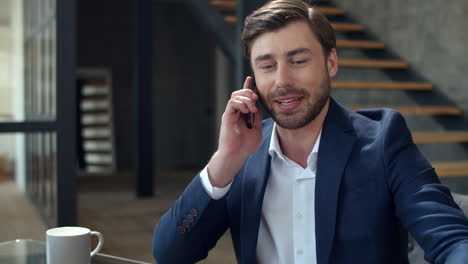 Happy-businessman-talking-phone-in-office.-Top-manager-discussing-documents.