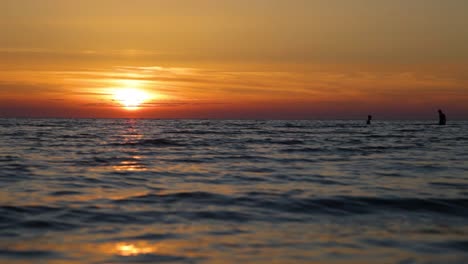 Two-guys-are-swimming-in-the-sea-at-sunset,-faces-are-not-visible,-human-silhouettes