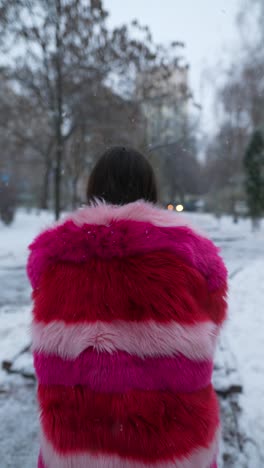 mujer con un abrigo de piel rosa y rojo en la nieve