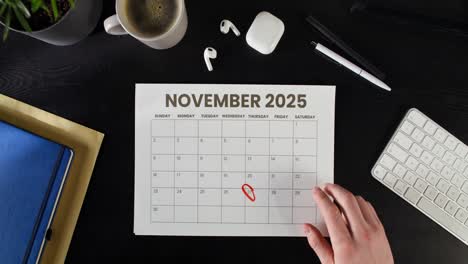 november 2025 calendar with hand marking a date