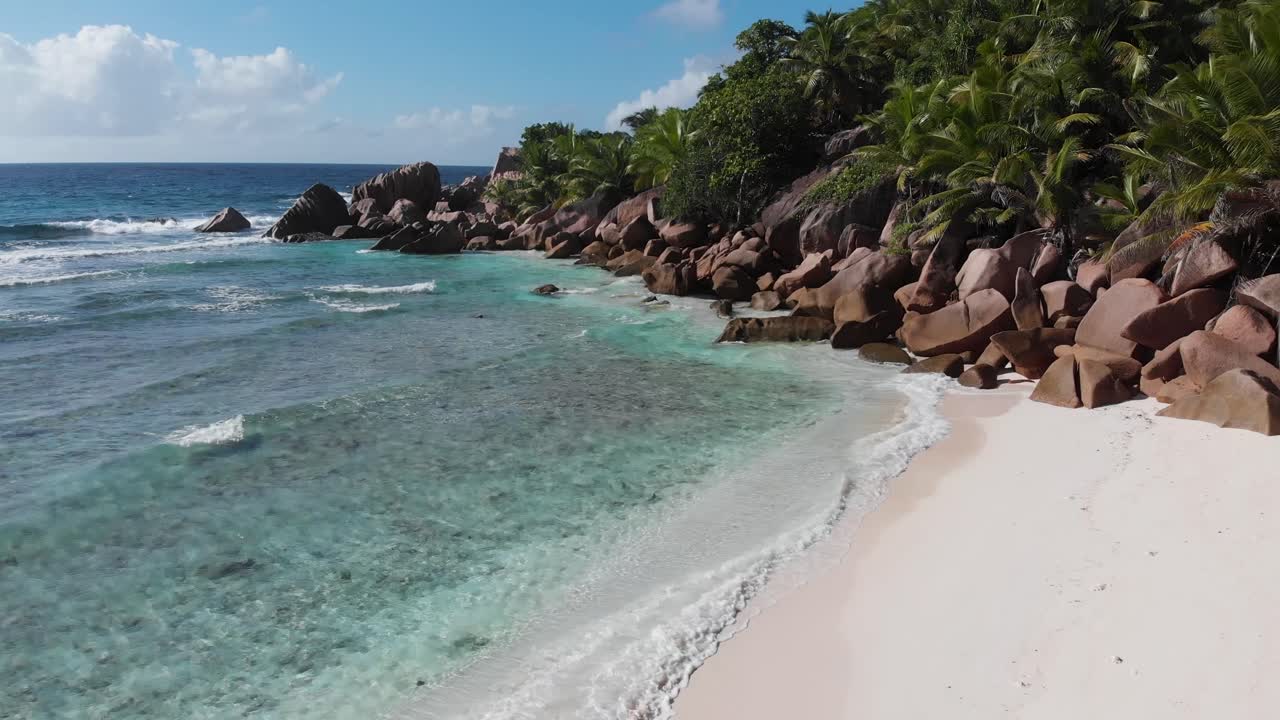 Flygvy över de vita stränderna och det turkosa vattnet vid Anse Coco, Petit Anse och Grand Anse på La Digue, en ö i Seychellerna