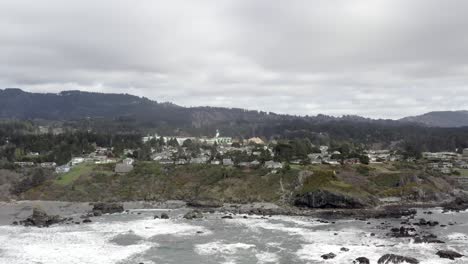 brookings city on rugged oregon coastline, houses on clifftop, aerial rising