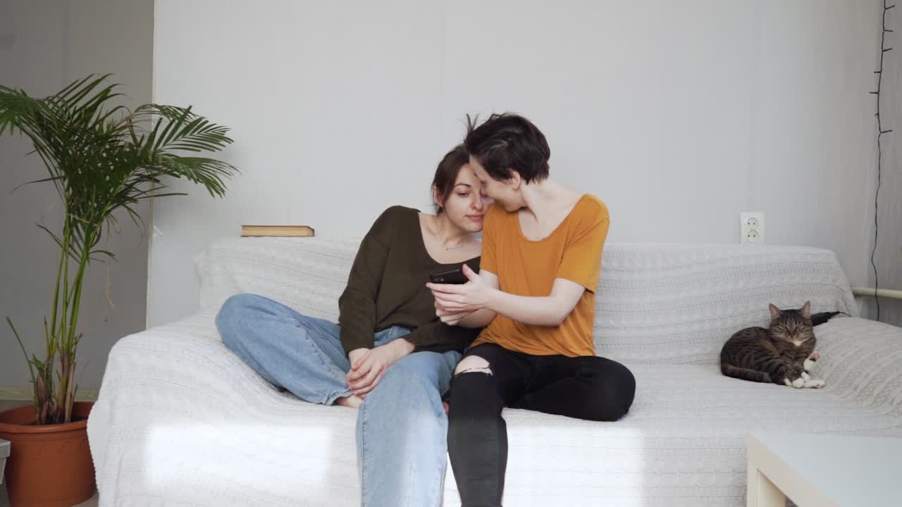 두 소녀가 스마트폰을 보고 소통하고 미소 짓습니다.