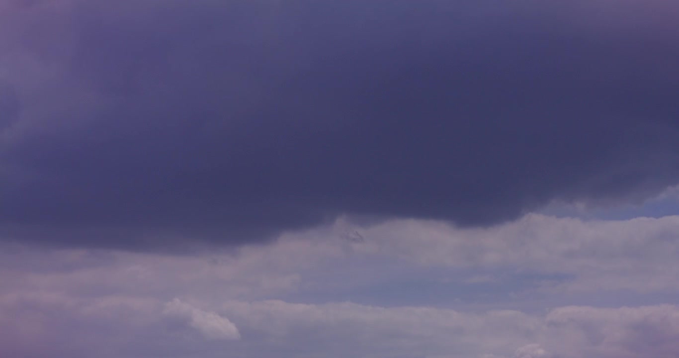 Ominous Dark Clouds and Lighter Clouds Moving Across a Purple Sky