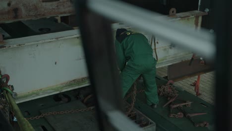 man in green boiler suit moving heavy chain in preparation for lifting operation