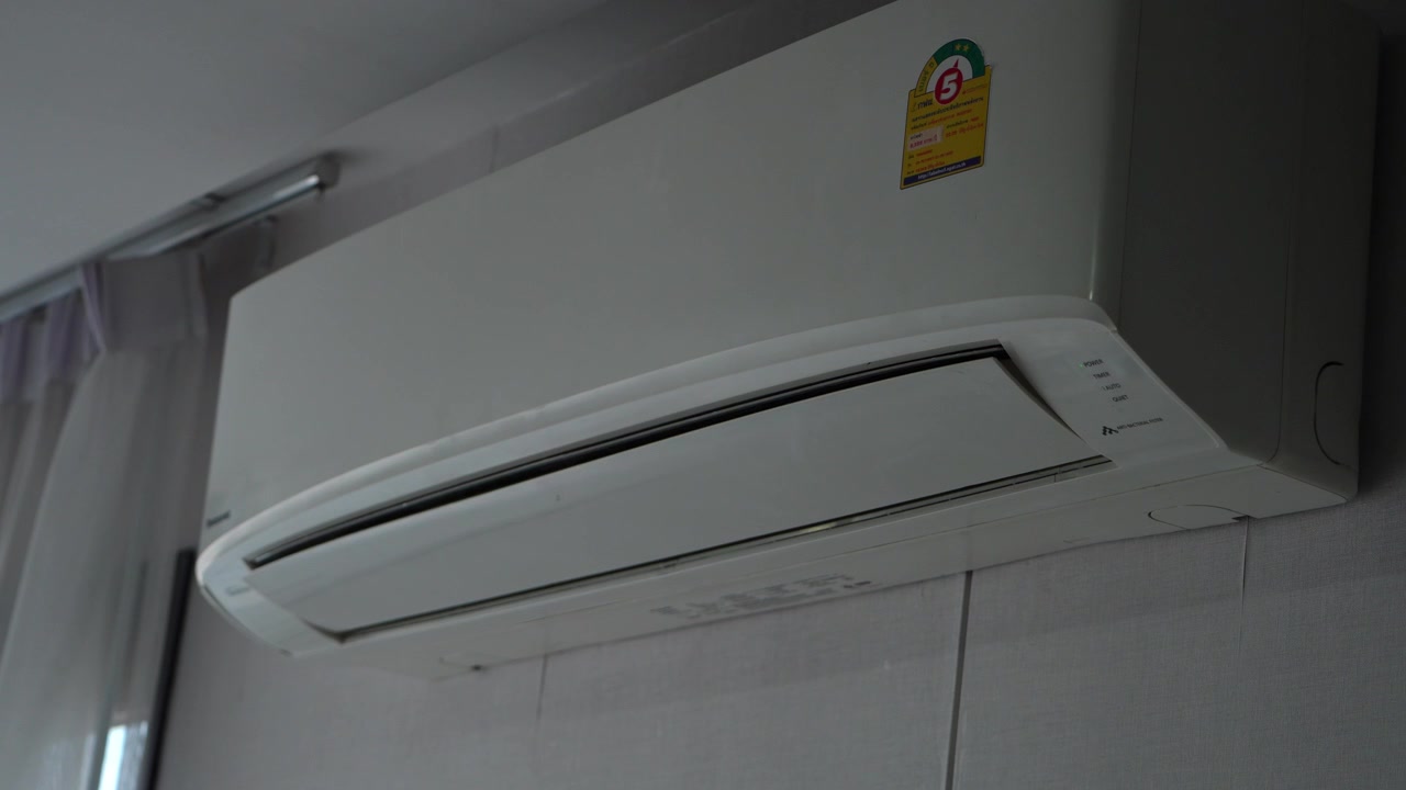 Close-up of a wall-mounted air conditioner operating with moving vent blades during cooling.