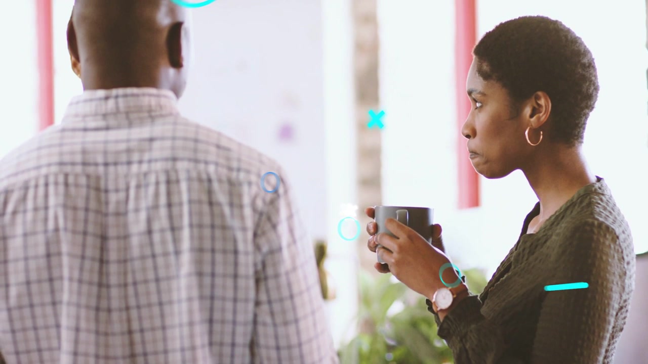 Woman sipping mug while man standing, sparking teal white graphics drifting across office on break