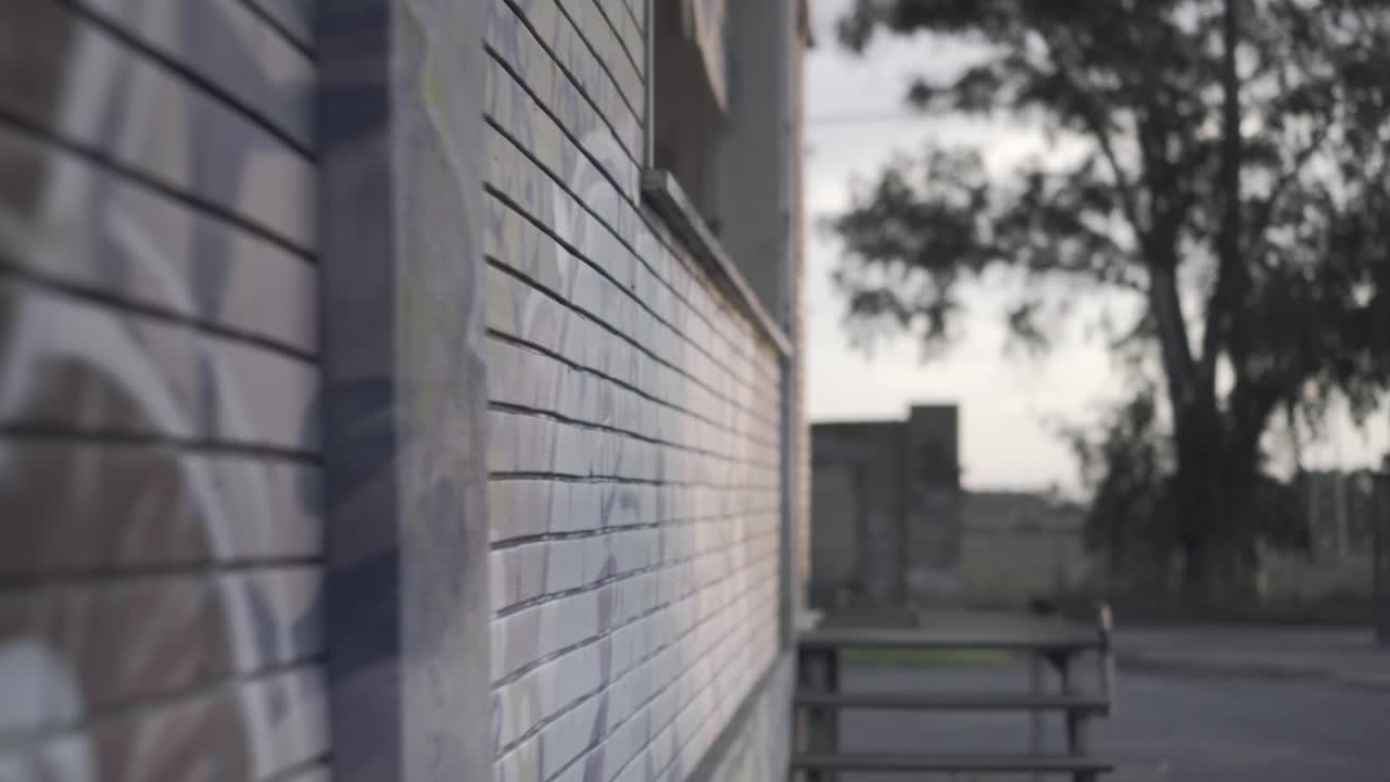 Abandoned warehouse - backwards close up along a wall with mural at sunset