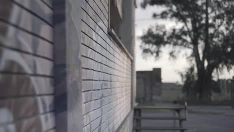 abandoned warehouse - backwards close up along a wall with mural at sunset