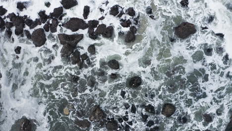 aerial view of ocean waves crashing against rocks along shore, god's thumb oregon coast, top down ascending