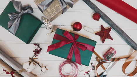 creative hobby. gift wrapping. packaging modern christmas present boxes in stylish gray paper with satin red ribbon. top view of hands on white wood table with fir tree branches, decoration