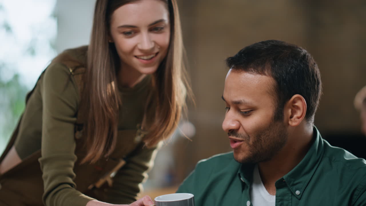chica dando café colega sentado en la oficina coworking primer plano. hombre hablando mujer