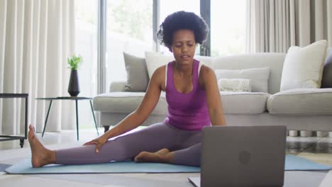 feliz afroamericano usando ropa deportiva, haciendo ejercicio, usando una computadora portátil