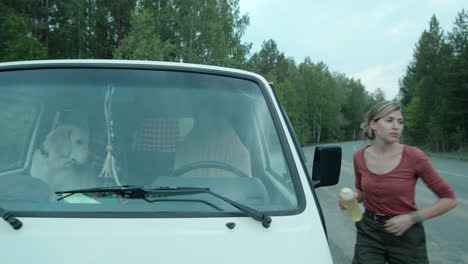 Woman-Drinking-Water-and-Petting-Dog-during-Car-Stop