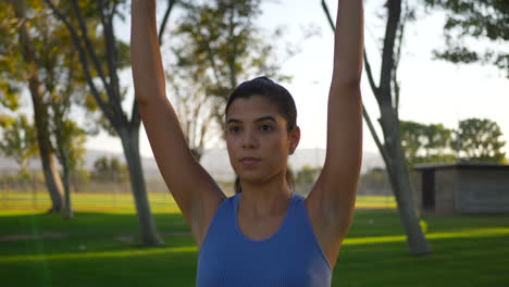 Cerrar-A-Una-Mujer-Joven-Haciendo-Ejercicio-En-El-Parque-Con-Pesas-Haciendo-Hombro-Deltoides-Levanta-Cámara-Lenta