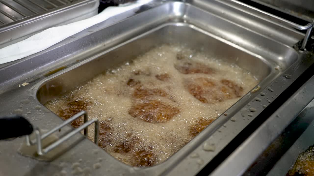Crispy golden fried food being prepared in a bustling kitchen during a busy lunch rush