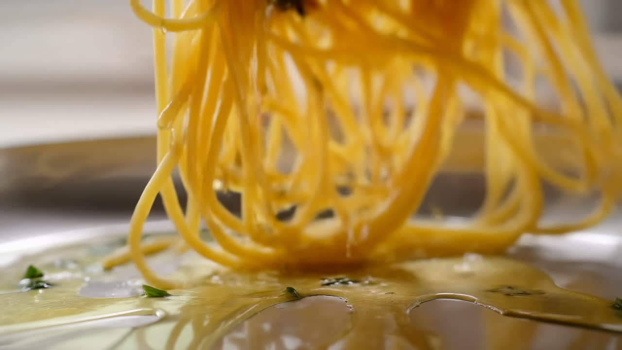 Spaghetti che gocciolano olio d'oliva dorato, primo piano di un cuoco casalingo che solleva fili lucidi con una forchetta sopra la porcellana.
