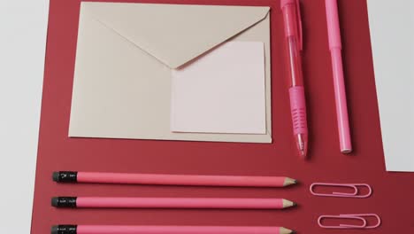 close up of pens, pencils and stationery arranged on red background, in slow motion