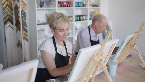 young woman teaches elderly students to draw pictures in courses for rehabilitation and development of retirees