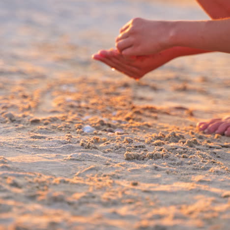 close-up boys hands playing in sand at sunset. boy putting different pebbles into sand in the evening. child is having fun during summer holidays.
