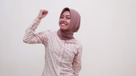 young asian muslim girl celebrating her victory with fist or cleched hands