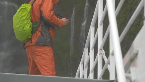 tourist standing under waterfall