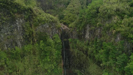 cascada casi seca rodeada de escarpados acantilados cubiertos de plantas exuberantes