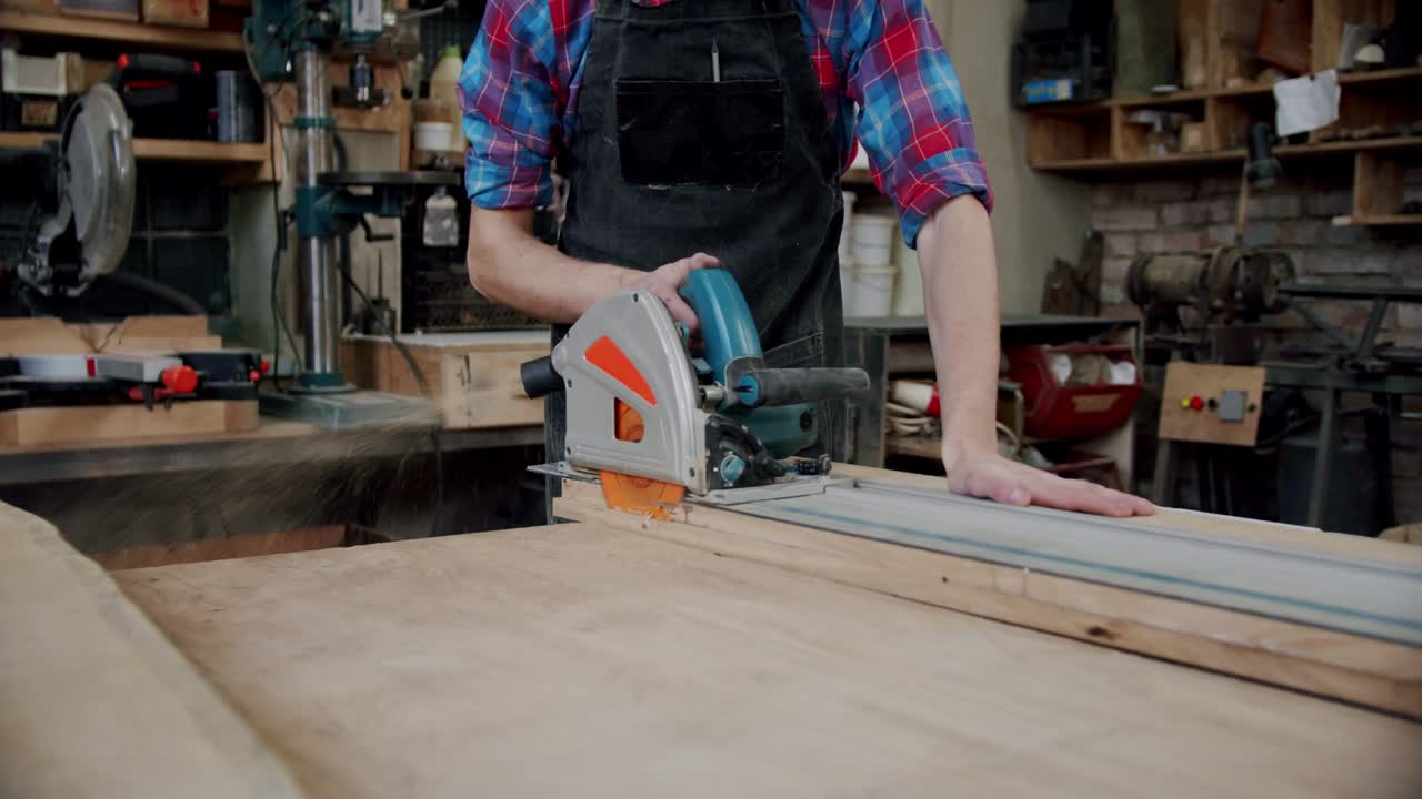el maestro corta una tabla de madera con una sierra circular en el taller de carpintería de un pequeño fabricante de muebles. cámara lenta
