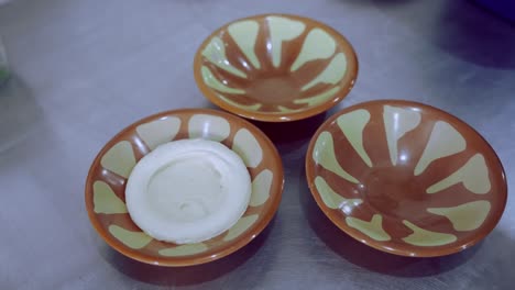 person hand spreading hummus around dish, designing plate