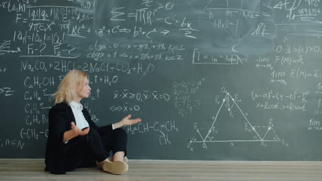 stressed student sitting on floor in front of chalkboard