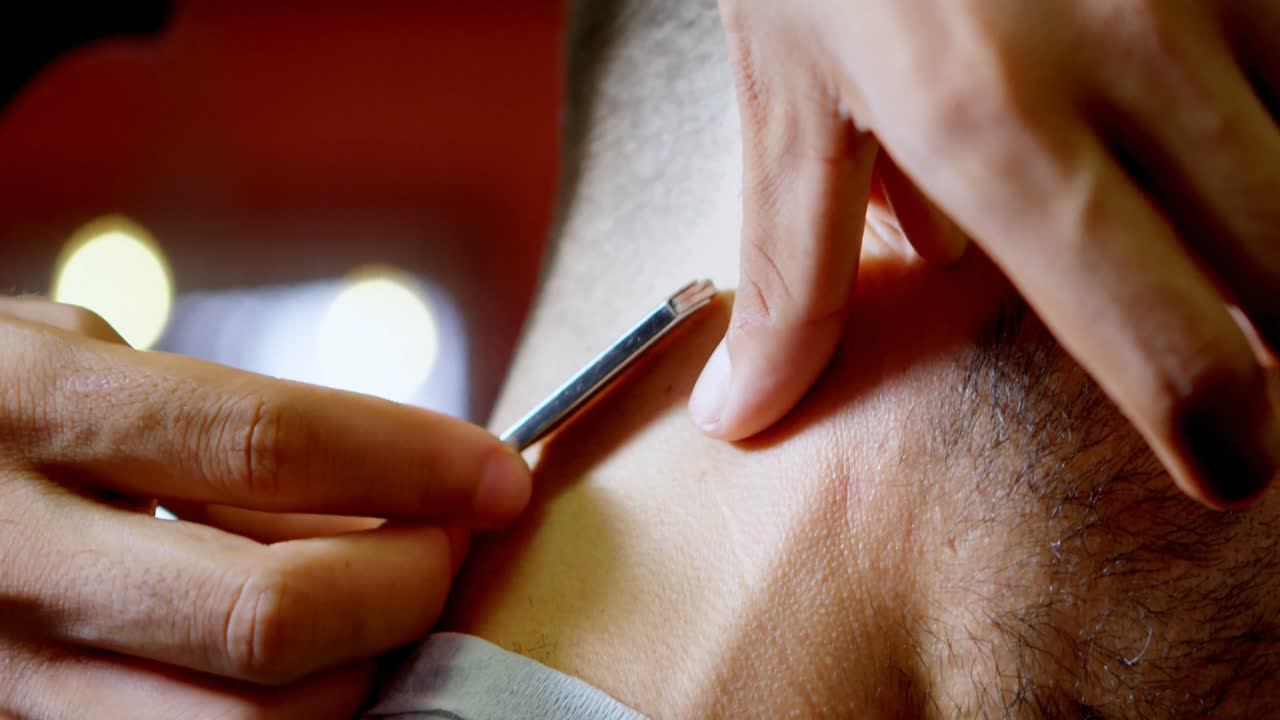 Barber trimming client hair with straight razor at barber shop 4k