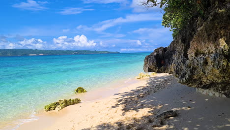 Playa-Exótica-Con-Arena-Blanca-Bajo-Rocas-Y-Sombra-De-árboles-En-Una-Isla-Tropical