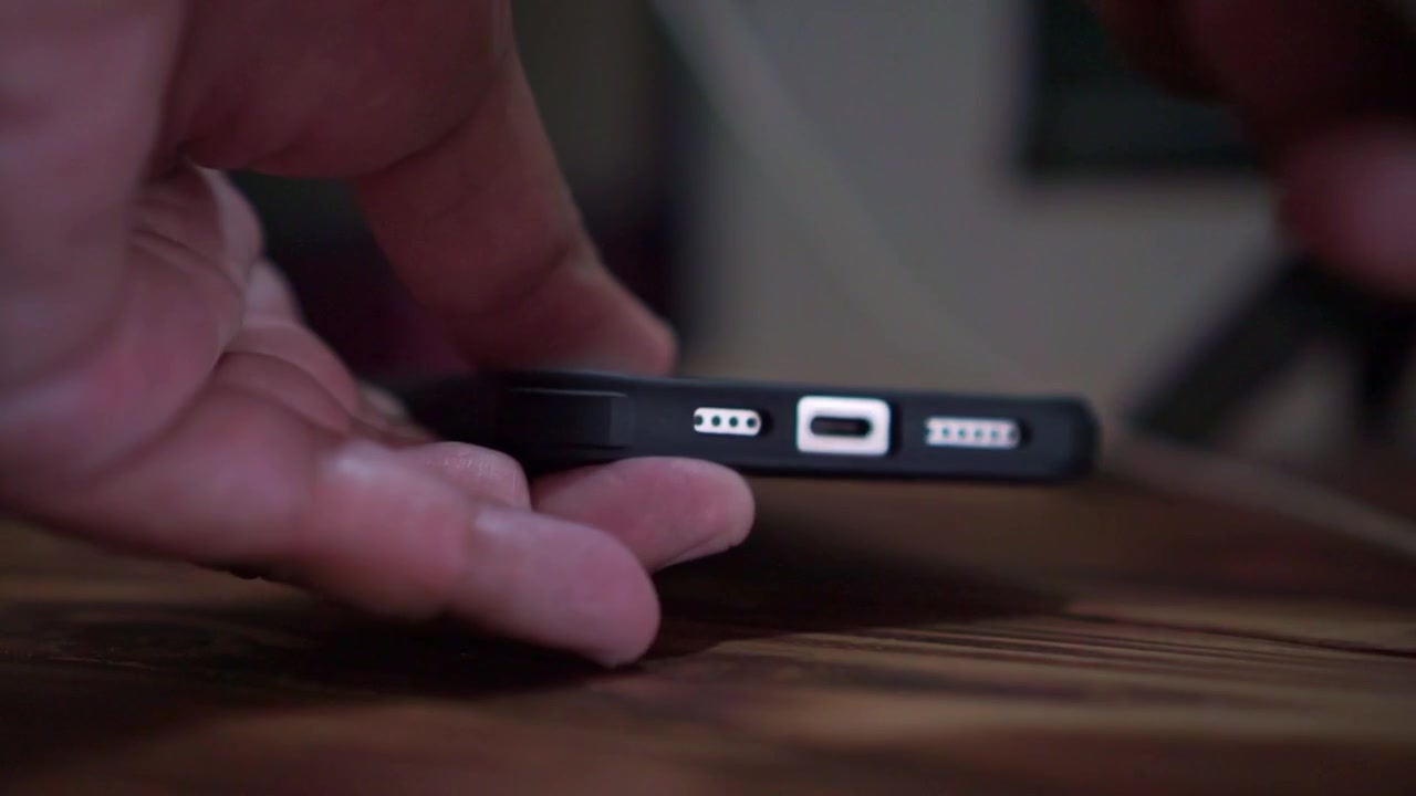 Persona che scollega il cavo USB-C dalla porta di ricarica dello smartphone, ripresa ravvicinata, tecnologia per telefoni cellulari, scena filmata su sfondo scuro