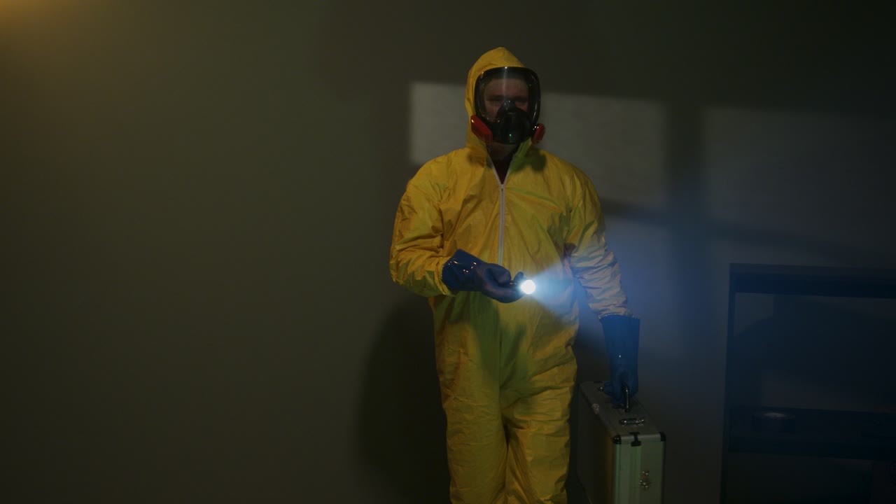 Hazmat suit wearing man explores a dark room