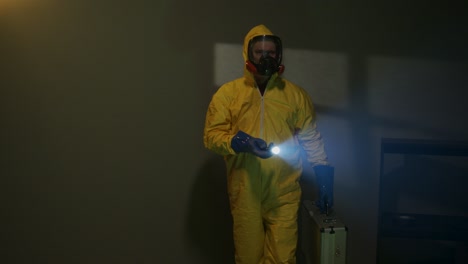 Hazmat-suit-wearing-man-explores-a-dark-room