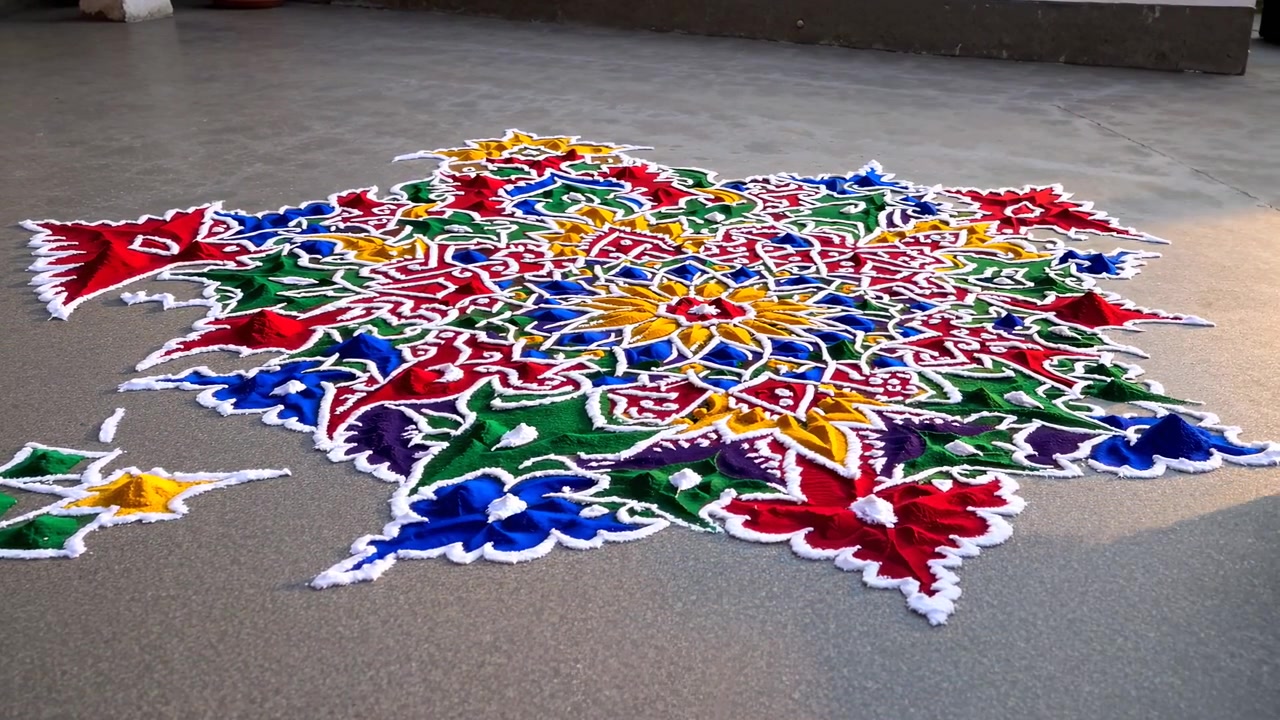 Persona che crea un motivo Rangoli colorato sul pavimento
