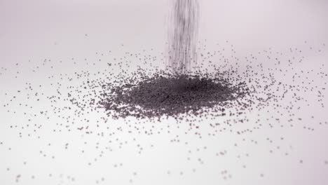 dry organic poppy seeds fall in heap against white background in studio