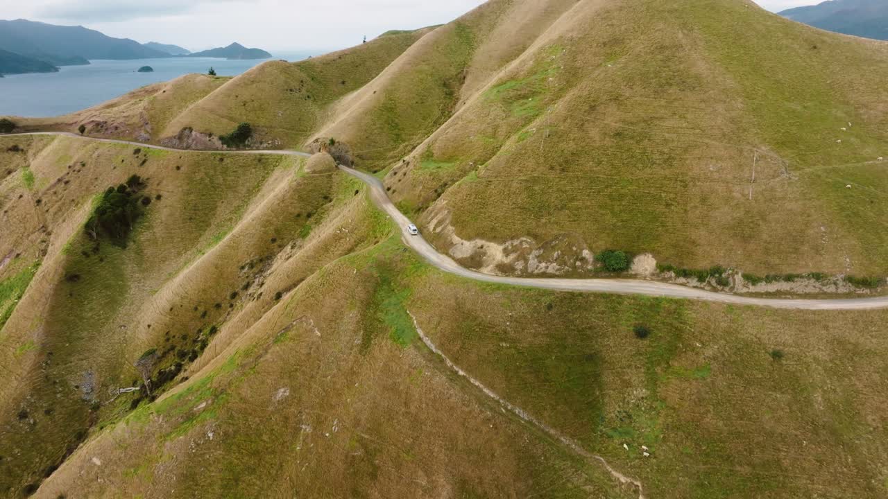 impresionante vista aérea de una autocaravana que viaja a lo largo de una remota carretera montañosa hacia el paso francés de te aumiti en marlborough sounds, isla sur de nueva zelanda aotearoa
