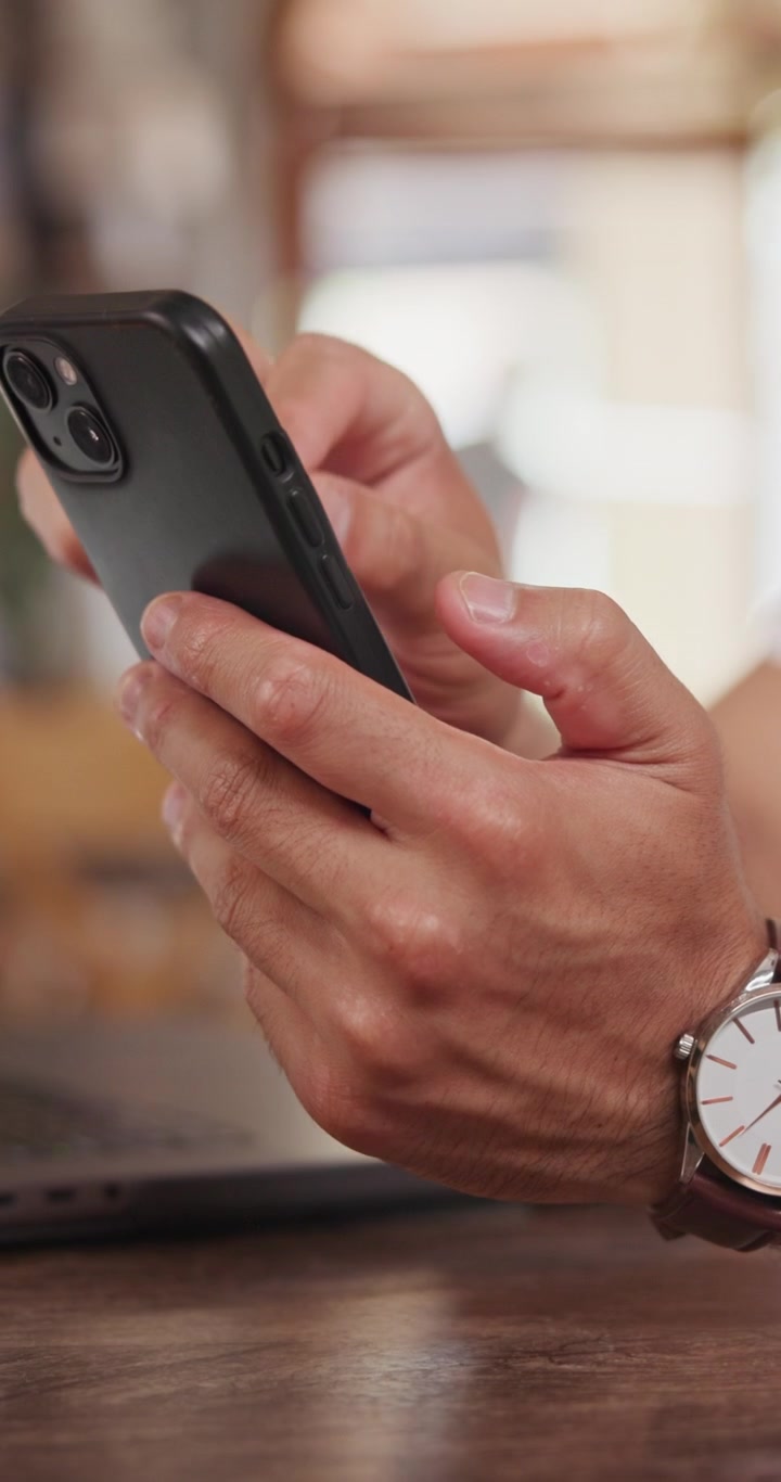 Primo piano di un uomo che usa uno smartphone in un bar