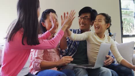 Family-giving-high-five-while-using-laptop-in-living-room-4k
