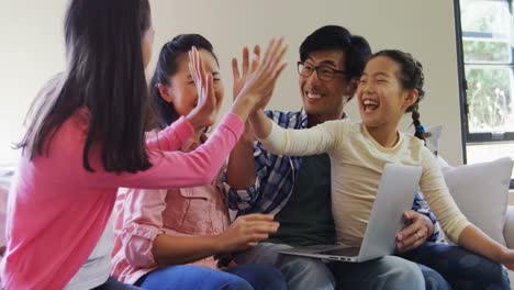 family giving high five while using laptop in living room 4k